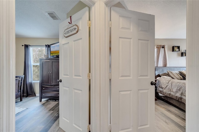 corridor featuring a textured ceiling and light hardwood / wood-style flooring