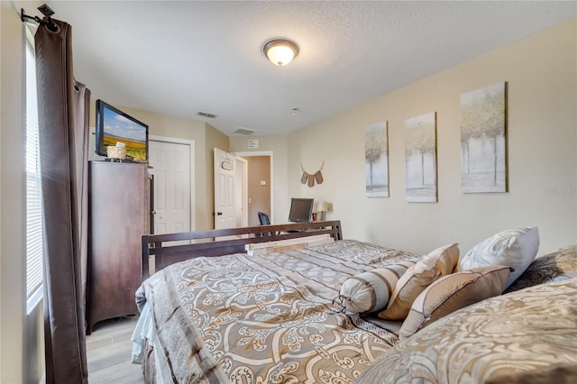 bedroom featuring a textured ceiling and light hardwood / wood-style flooring