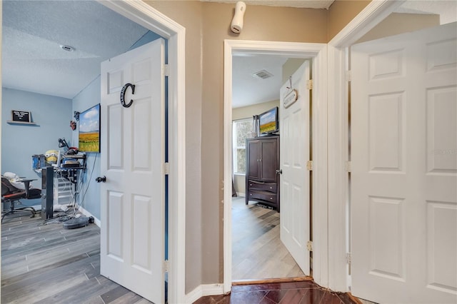 hall with a textured ceiling, lofted ceiling, and wood-type flooring