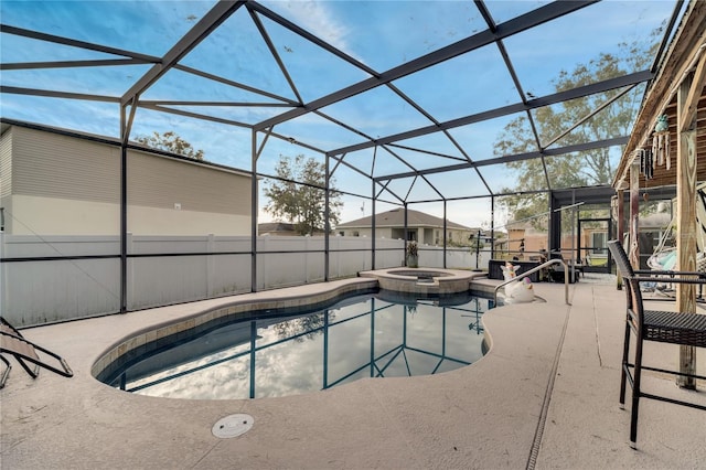 view of pool with a patio, glass enclosure, and an in ground hot tub