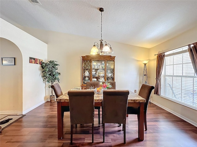 dining area featuring dark hardwood / wood-style floors, vaulted ceiling, a textured ceiling, and a notable chandelier