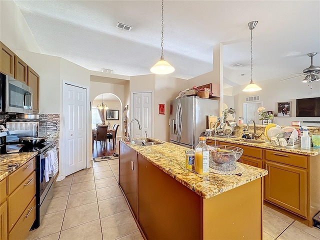 kitchen with a kitchen island with sink, sink, decorative light fixtures, and appliances with stainless steel finishes