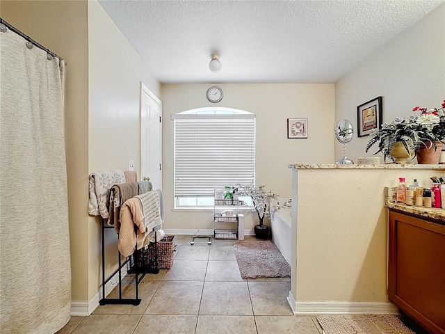 bathroom featuring tile patterned flooring, vanity, a bath, and a textured ceiling