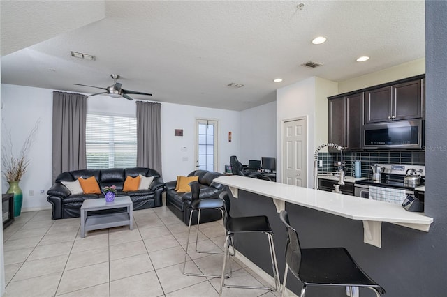 kitchen with appliances with stainless steel finishes, a breakfast bar, a textured ceiling, and tasteful backsplash