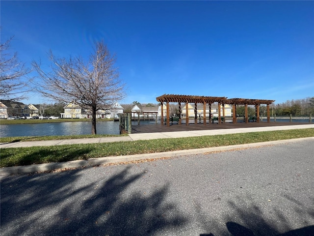 surrounding community with a water view and a pergola