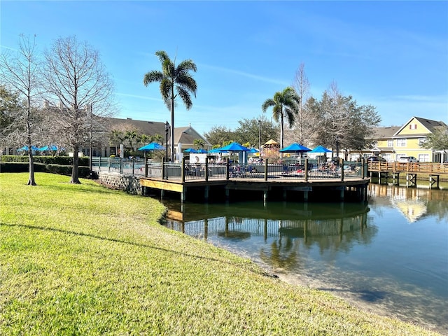 view of dock with a yard and a water view