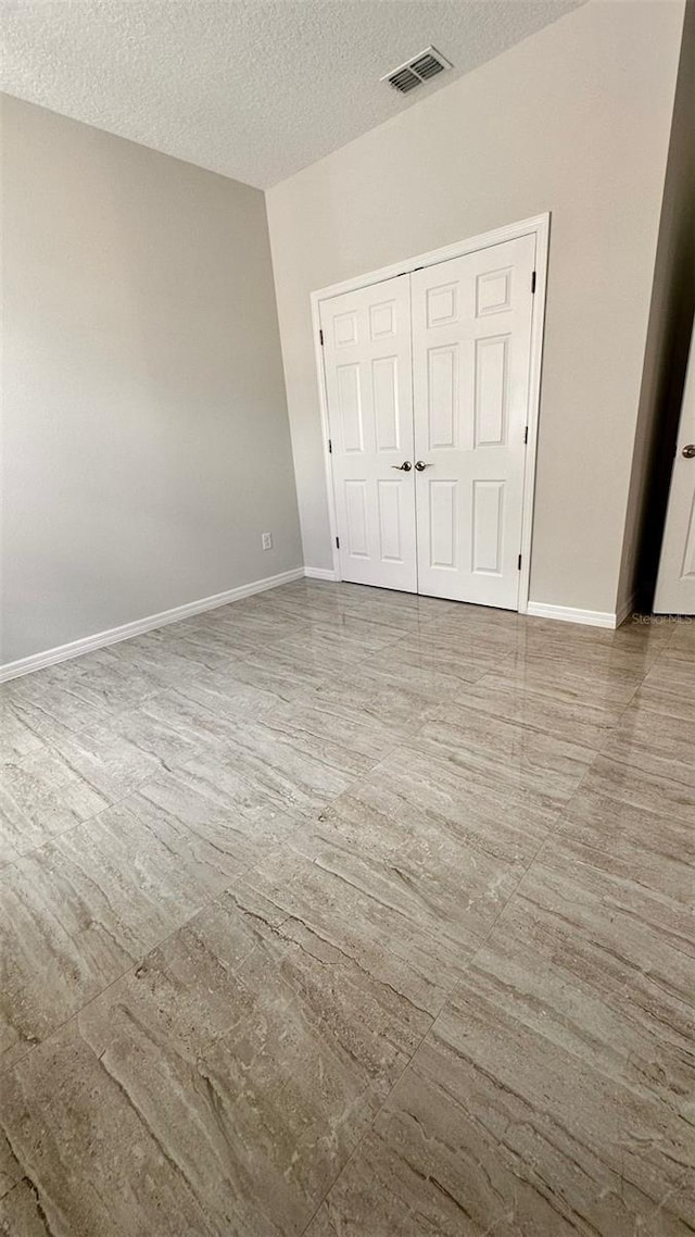 unfurnished bedroom with a textured ceiling and a closet