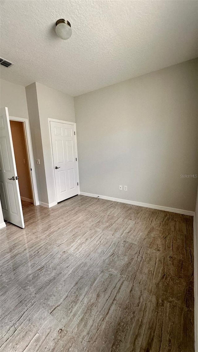 empty room featuring wood-type flooring and a textured ceiling