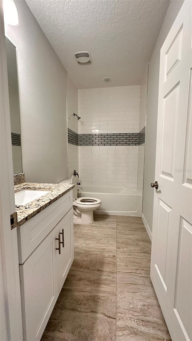 full bathroom with toilet, tiled shower / bath combo, a textured ceiling, and vanity