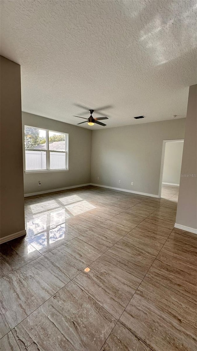 empty room with a textured ceiling and ceiling fan