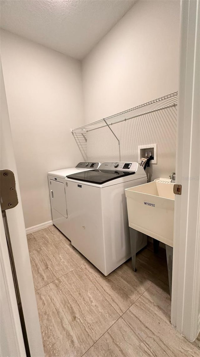 laundry area with independent washer and dryer, a textured ceiling, and sink