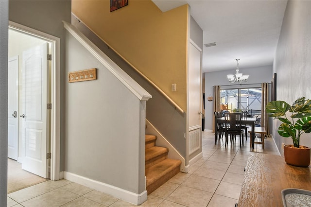 stairs featuring tile patterned floors and a chandelier