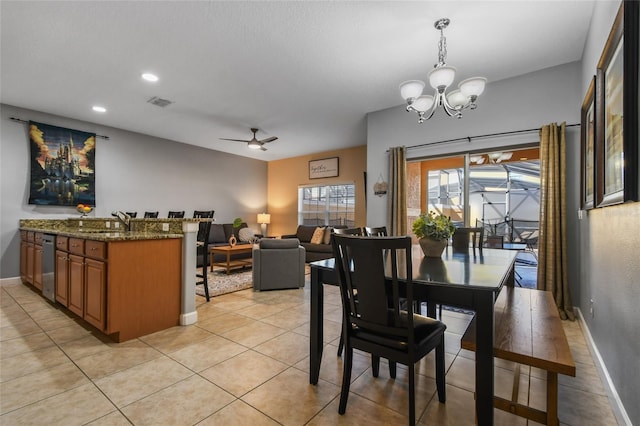 tiled dining area featuring sink and ceiling fan with notable chandelier