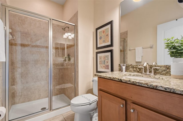 bathroom featuring toilet, a shower with shower door, tile patterned floors, and vanity