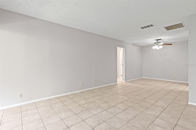 empty room with a textured ceiling, ceiling fan, and light tile patterned floors