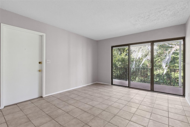 tiled empty room featuring a textured ceiling