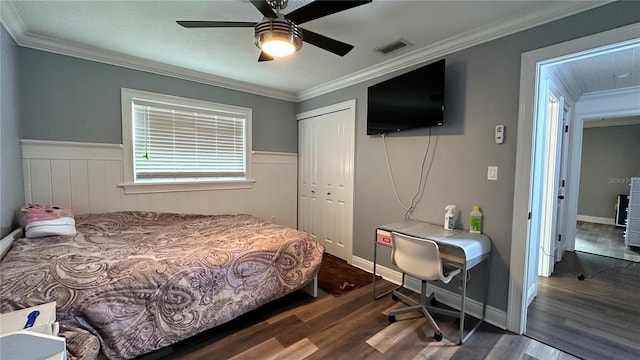 bedroom with dark wood-type flooring, ceiling fan, a closet, and crown molding