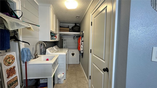 washroom featuring separate washer and dryer, cabinets, a textured ceiling, and light tile patterned floors