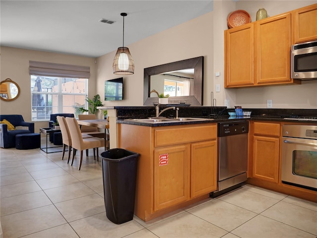 kitchen with stainless steel appliances, dark stone countertops, pendant lighting, and light tile patterned floors