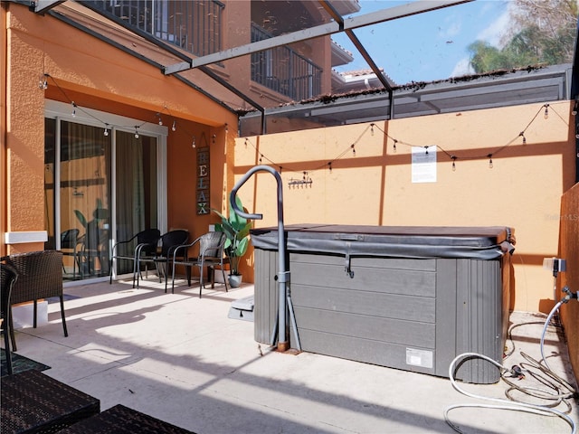 view of patio / terrace featuring a lanai and a hot tub