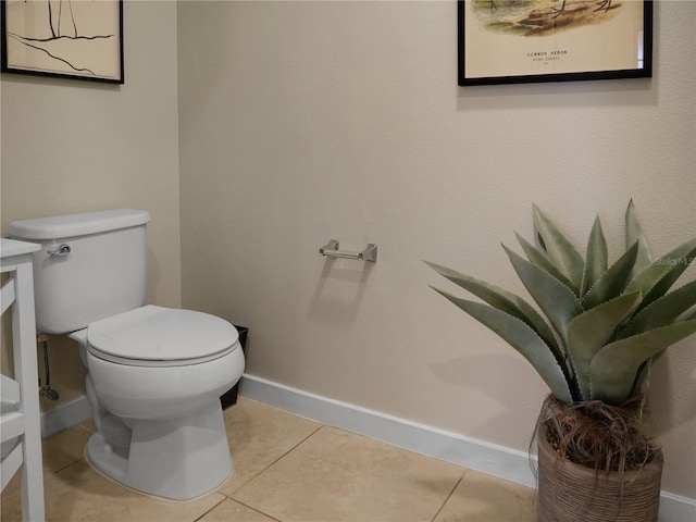 half bath with toilet, baseboards, and tile patterned floors