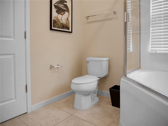 bathroom with toilet, a tub, baseboards, and tile patterned floors