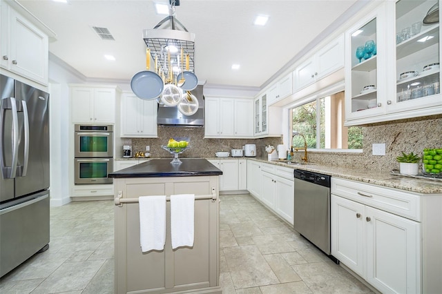 kitchen with stainless steel appliances, a center island, white cabinets, and sink