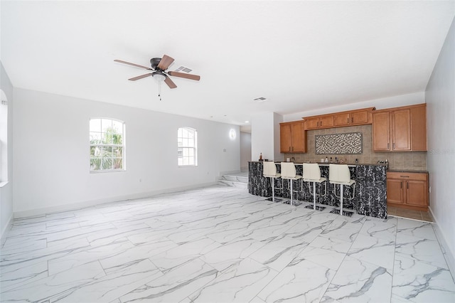 kitchen with tasteful backsplash, ceiling fan, and a kitchen breakfast bar