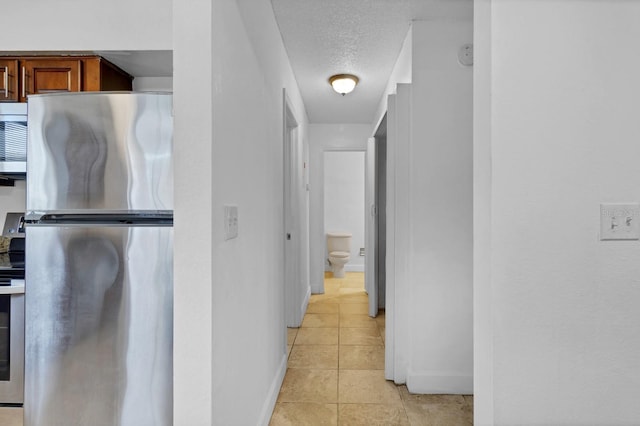 hall with light tile patterned floors and a textured ceiling