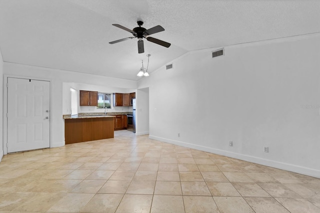 interior space featuring ceiling fan with notable chandelier, a textured ceiling, vaulted ceiling, sink, and light tile patterned flooring