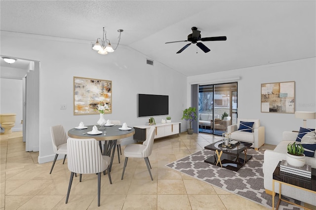 tiled dining room featuring ceiling fan with notable chandelier, a textured ceiling, and vaulted ceiling