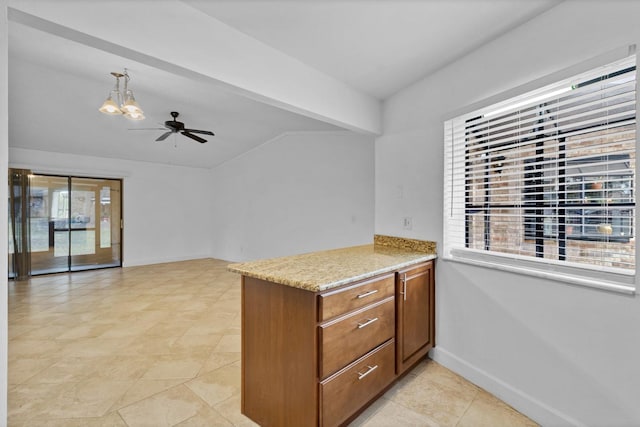 kitchen with ceiling fan with notable chandelier, light stone counters, and kitchen peninsula