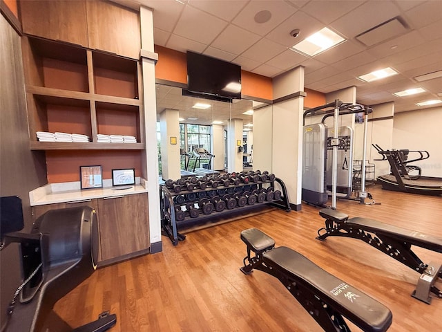 workout area with a drop ceiling and light wood-type flooring