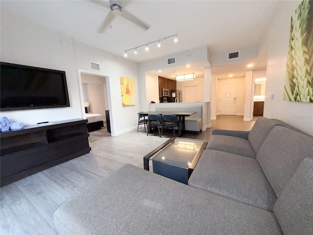 living room with ceiling fan, rail lighting, and light hardwood / wood-style flooring