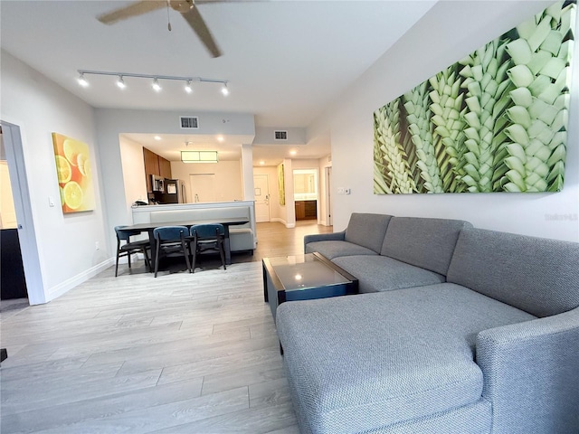 living room with track lighting, ceiling fan, and light wood-type flooring