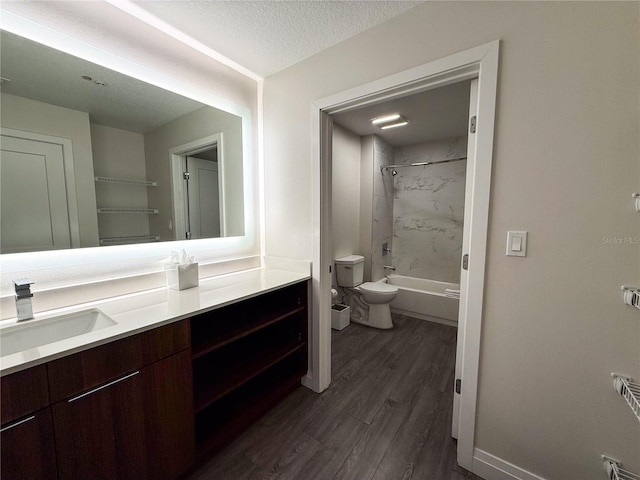 full bathroom featuring tiled shower / bath combo, vanity, wood-type flooring, a textured ceiling, and toilet