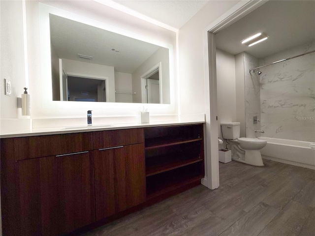 full bathroom featuring tiled shower / bath combo, vanity, hardwood / wood-style floors, and toilet