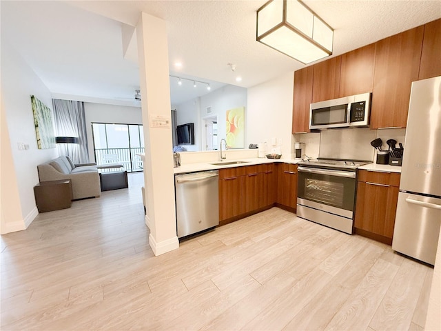 kitchen with sink, light hardwood / wood-style flooring, a textured ceiling, and appliances with stainless steel finishes