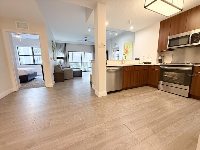 kitchen featuring a healthy amount of sunlight, ceiling fan, stainless steel appliances, and light hardwood / wood-style flooring