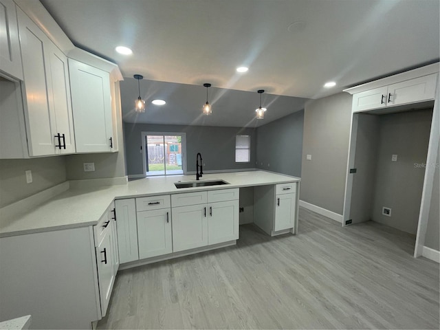 kitchen with sink, white cabinetry, light hardwood / wood-style flooring, kitchen peninsula, and pendant lighting