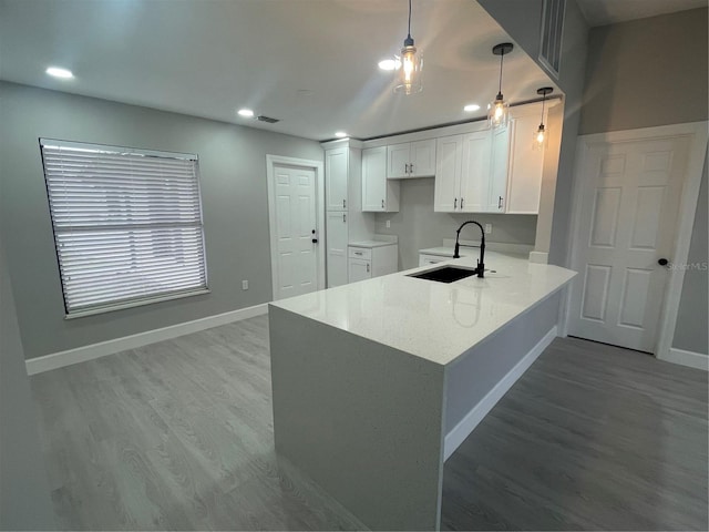 kitchen featuring decorative light fixtures, white cabinetry, wood-type flooring, sink, and kitchen peninsula