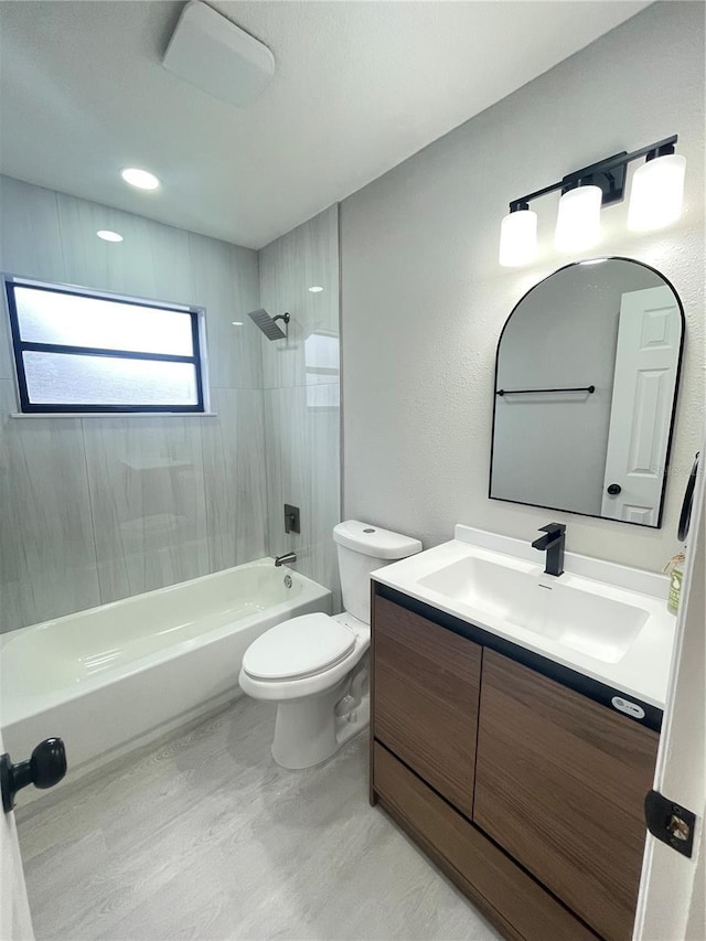 full bathroom featuring tiled shower / bath, vanity, and toilet