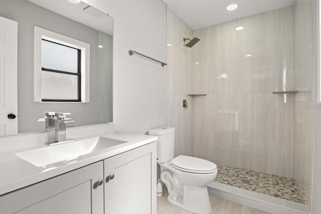 bathroom with vanity, toilet, and a tile shower