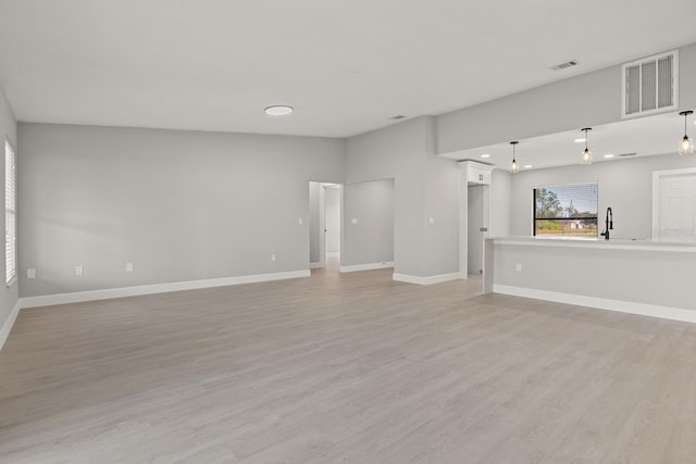 unfurnished living room featuring sink and light hardwood / wood-style flooring