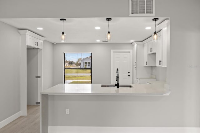 kitchen featuring decorative light fixtures, kitchen peninsula, sink, and white cabinets