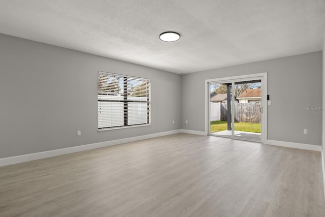 spare room with a textured ceiling and light hardwood / wood-style flooring