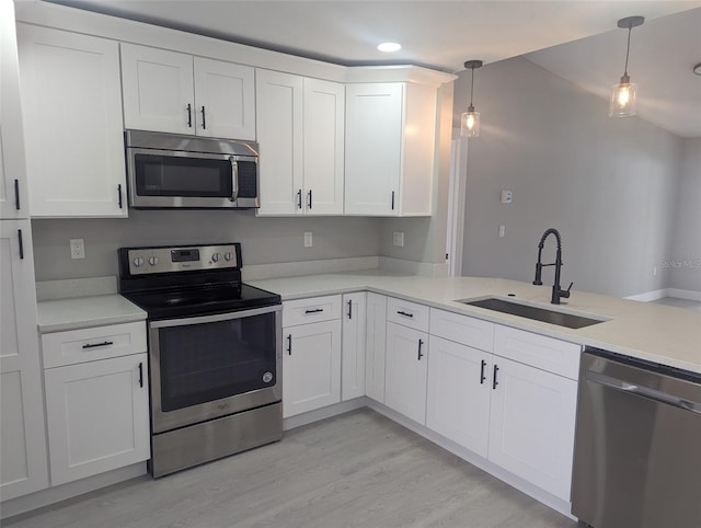 202 Cobalt Dr, Kissimmee, FL 34758 - kitchen with stainless steel appliances, light countertops, white cabinetry, light wood finished floors, and decorative light fixtures