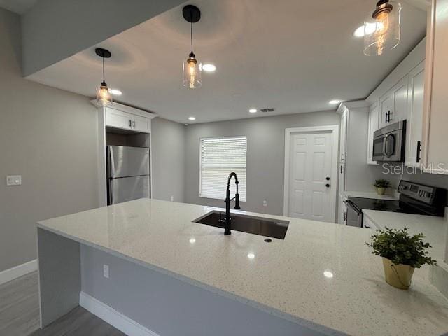 202 Cobalt Dr, Kissimmee, FL 34758 - kitchen featuring stainless steel appliances, light wood-type flooring, light stone counters, a peninsula, and recessed lighting