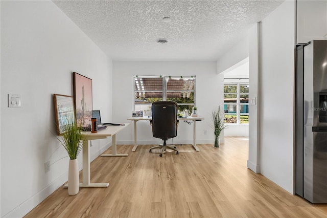 office area with a textured ceiling and light hardwood / wood-style flooring