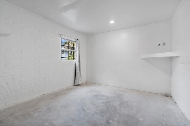 spare room with brick wall and concrete floors